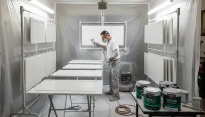 Painter refinishing Fresno kitchen cabinets with smooth, durable spray finish for lasting cabinet updates